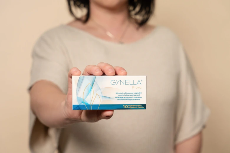 Žena drží krabičku vaginálních kapslí značky Gynella.
