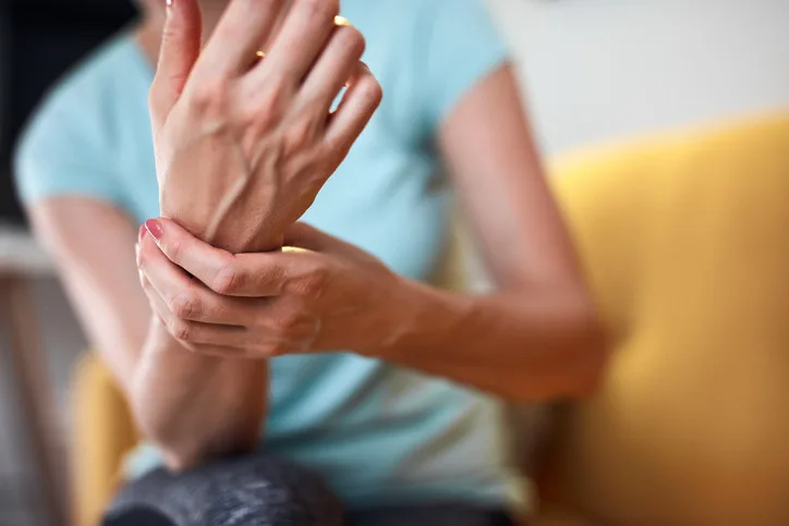 Žena drží bolavý zápěstí kvůli příznakům polyneuropatie.