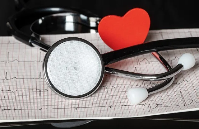 Stetoskop na EKG papíru s červeným srdcem jako symbol.