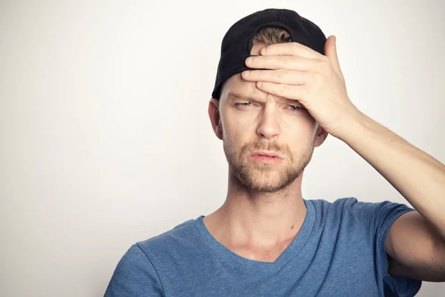 Muž s rukou na čele, který může mít příznaky mrtvice.