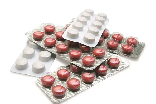 Blisterové balení s červenými a bílými tabletkami antibiotik.