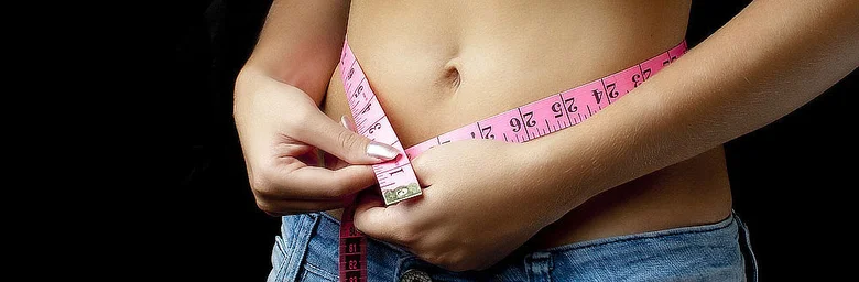 Woman measuring waist with tape measure