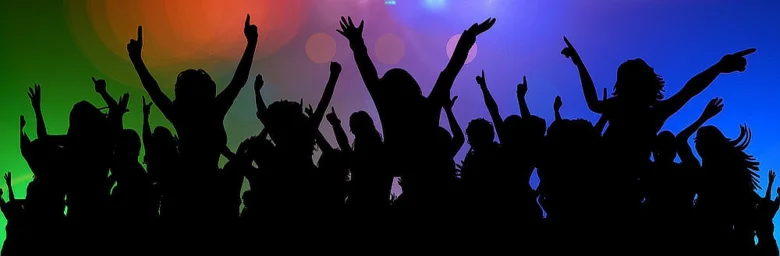 Stíny davu tančícího na party s barevným pozadím.