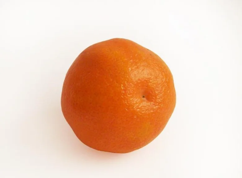 Jedna celá mandarinka na bílém pozadí.