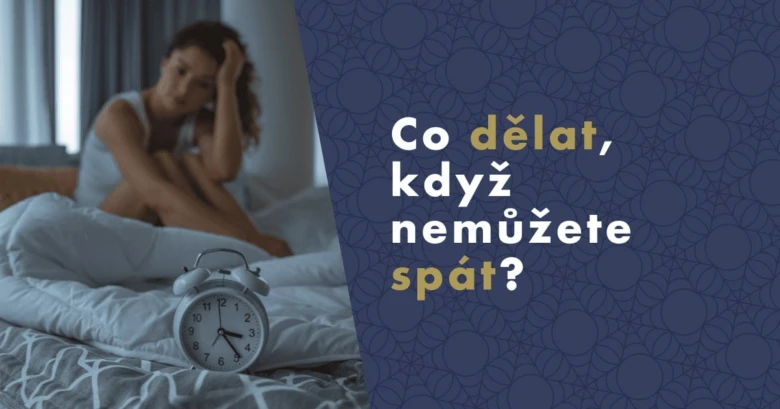 Žena sedí v posteli s budíkem a vypadá unaveně.