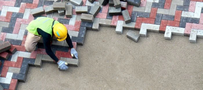 Stavebník položí dlažební kostky na přípravenou podkladovou vrstvu.