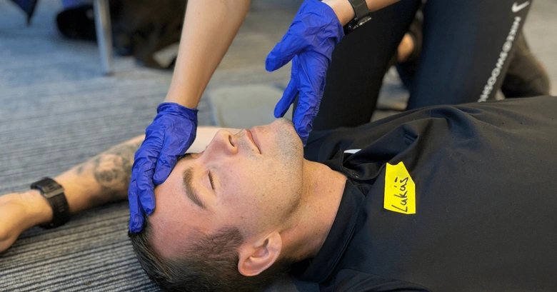 Fyzikální terapeut stabilizuje hlavu pacienta během rehabilitace.
