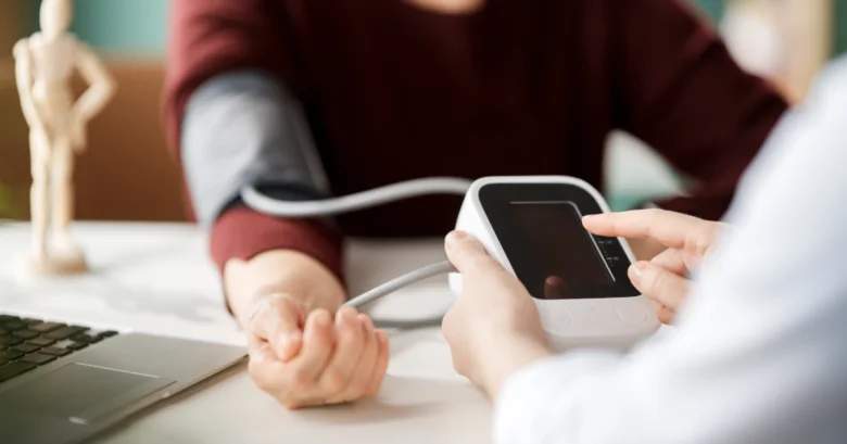 Lékař měří krevní tlak pacienta elektronickým přístrojem.