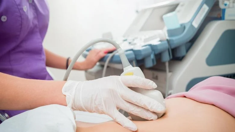 Ultrazvukové vyšetření břicha těhotné ženy lékařem v ordinaci.