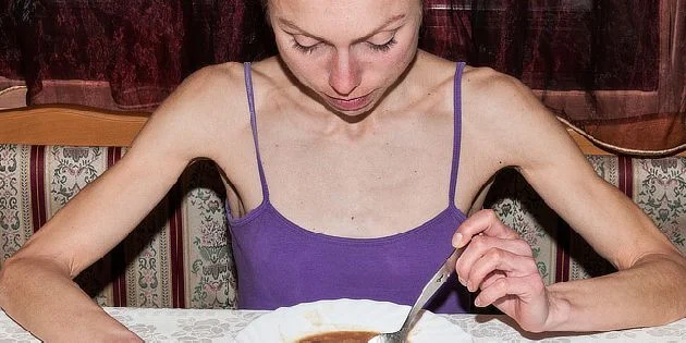 Tenká žena jí z misky, ilustrace příznaků anorexie.