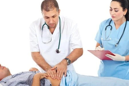 Lékař vyšetřuje pacienta, sestra zapisuje poznámky.