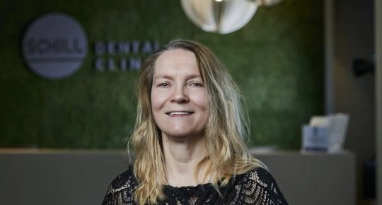 Žena usmívá se v recepci zubní kliniky.