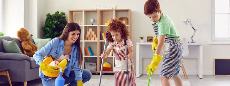 Rodina čistí dům s ekologickými prostředky a úsměvy na tvářích.