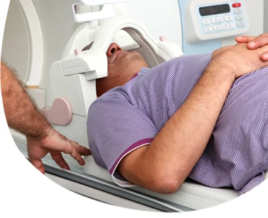 Muž leží na tomografu pro vyšetření hrtanu.