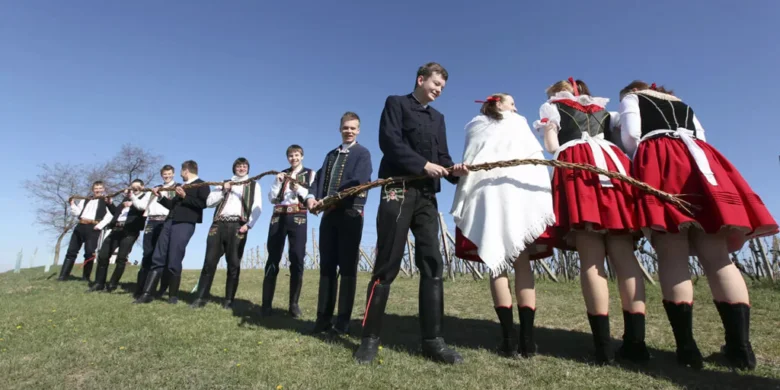 Lidé v lidových kostýmech drží větev vrby na Velikonoce.