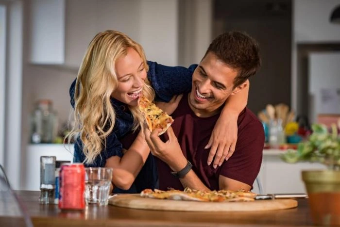 Pár sdílí pizzu v kuchyni - ilustrace blízkosti bez romantiky.