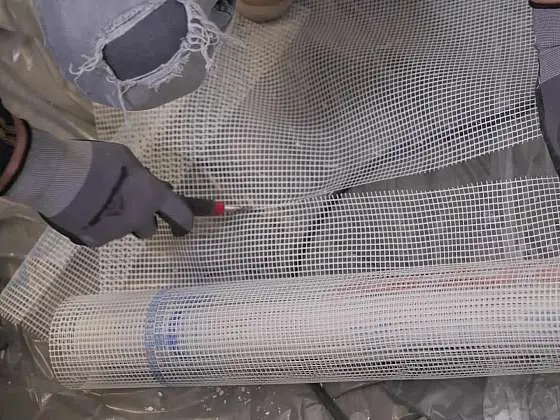 Ruční řezání perlinky na zdi během instalace.