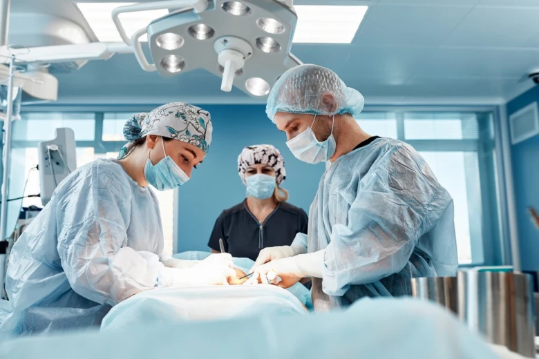 Tři lékaři operují pacienta v operační sále.