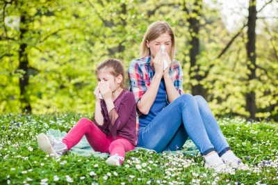 Žena s dcerou sedí na trávě v parcích a kašle.