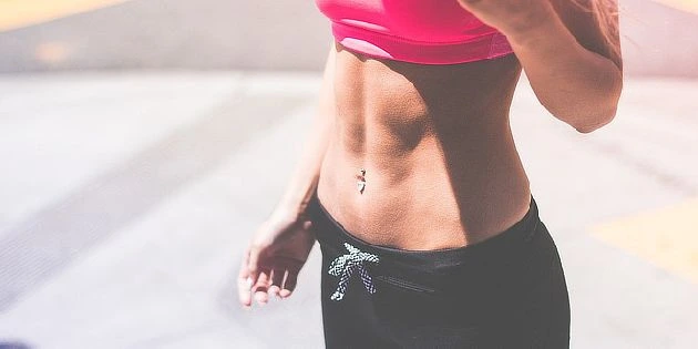 Žena v sportovním oblečení s viditelnými břišními svaly.