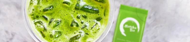 Sklenice zeleného čaje Matcha s ledem vedle balení.