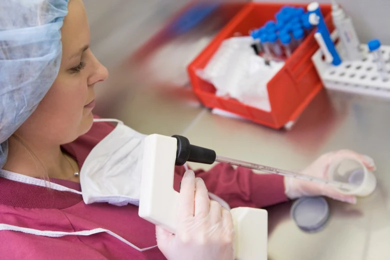 Žena v laboratoři s pipetou při umělém oplodnění.