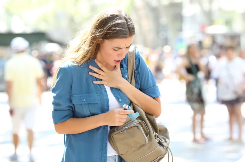 Žena používá inhalátor pro astma na ulici.