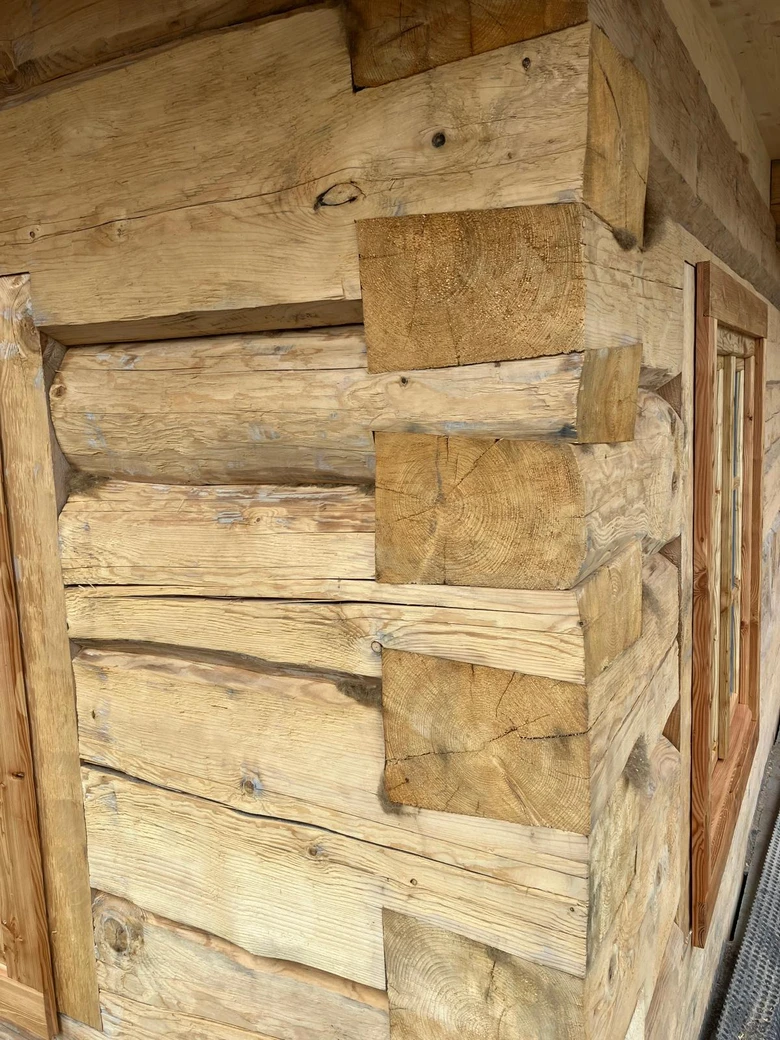 Detail dřevěného roubeného domu s viditelnými spoji trámů.