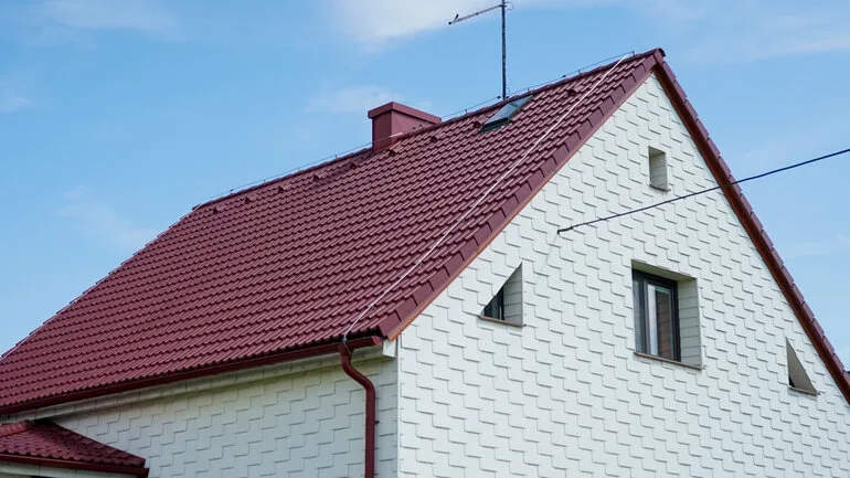 Červená střecha bílého rodinného domu s okny.