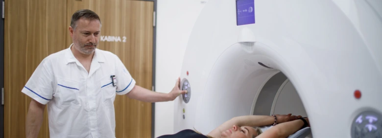 Lékař pomáhá pacientovi do magnetické rezonance pro vyšetření.