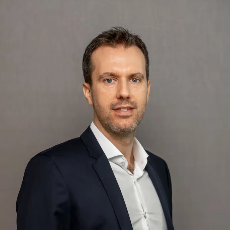 Profesionální portrét muže v obleku na šedém pozadí.