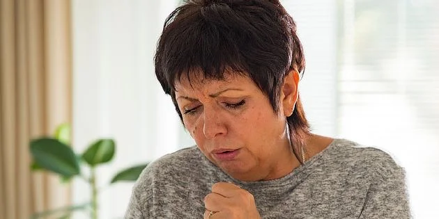 Žena kašle v interiéru jako příznak plicního emfyzému.