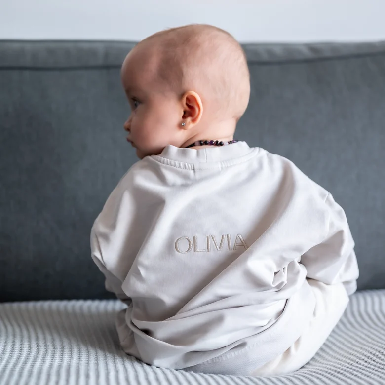 Mimořádě sedí v bílé košili s vyšívaným jménem OLIVIA.