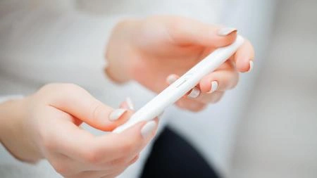 Ruce drží chytré telefon při hledání informací o těhotenské cholestáze