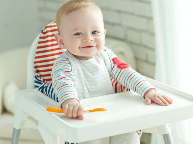 Baby in high chair with spoon