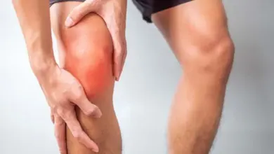 Muž drží bolestivé koleno s červenou kůží.