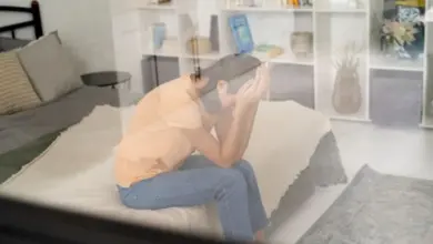 Osoba sedí na posteli s rukama před obličejem při pocitu derealizace.