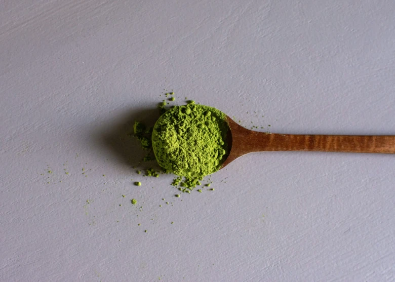 Dřevěná lžička s jemným zeleným práškem z čaje Matcha.