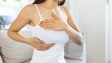 Žena drží ruce na prsou a břiše kvůli bolesti.