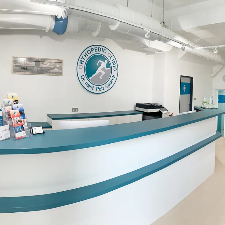 Recepce ortopedické kliniky v Plzni s logem na zdi.