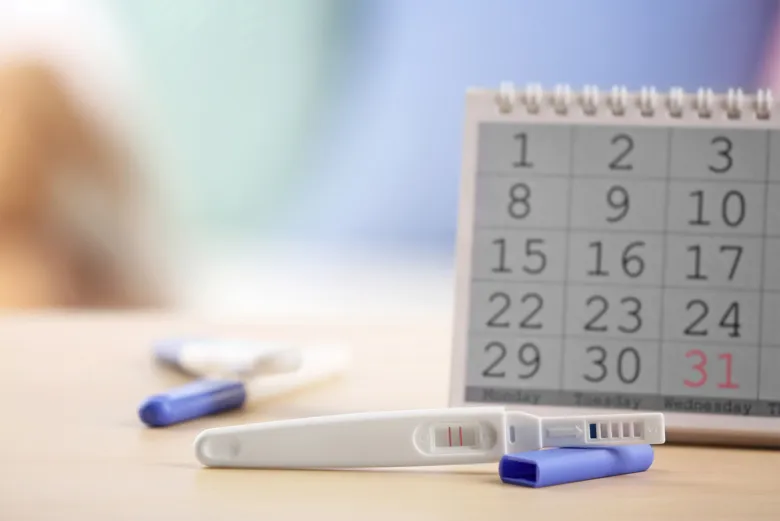 Těhotenský test vedle kalendáře s označeným datem.
