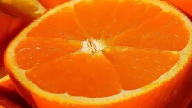 Čerstvý pomeranč nakrájený na polovinu s viditelnými segmenty.