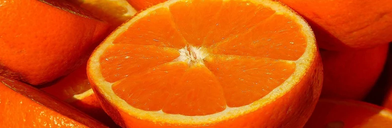 Čerstvý pomeranč nakrájený na polovinu s viditelnými segmenty.