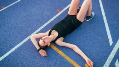 Žena leží na atletickém dráze po náročném tréninku.