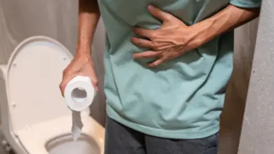 Muž v toaletě s příznaky průjmu drží si břicho.