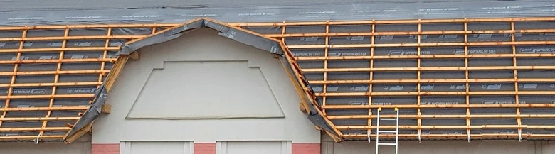 Střecha s nainstalovanou izolační fólií pod dřevěnými latemi.