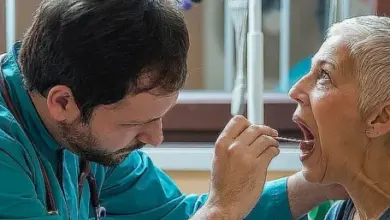 Lékař vyšetřuje ústní dutinu starší ženy pro podezření na rakovinu jazyka.