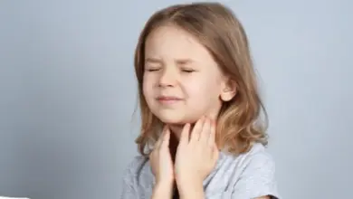 Dívka pláčící a držící si bolavé hrdlo.