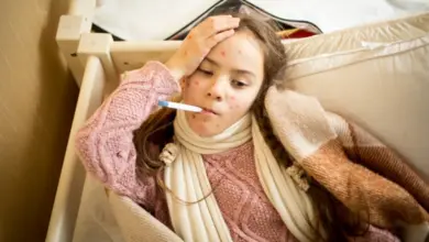 Dívka s neštovicemi leží v posteli s teploměrem ve svém ústech.