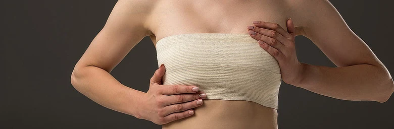Žena s obvazem na prsu po operaci nádoru.